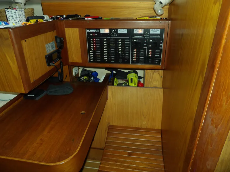 Slide: The Image of Navigation station of a 2000 Hunter 460 sailboat with control panels and wooden cabinetry. - 42