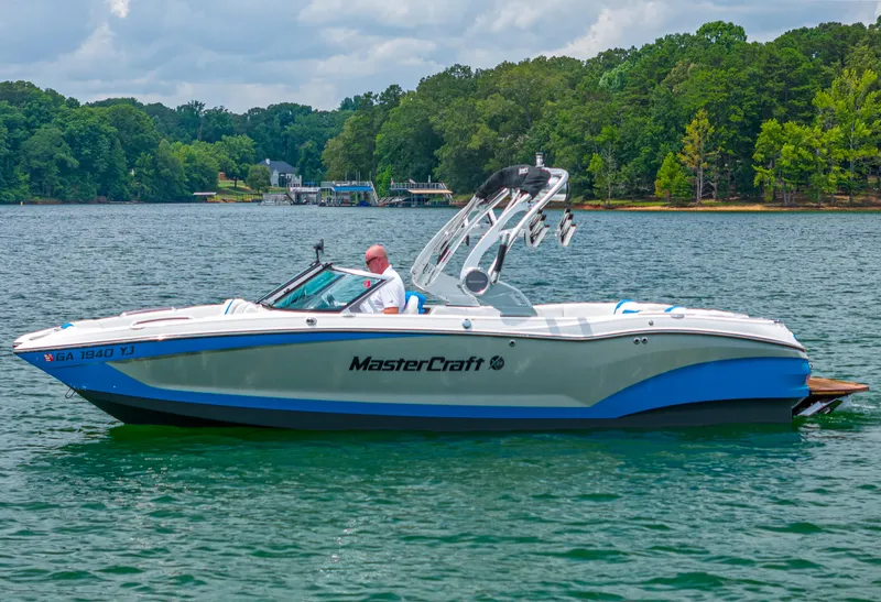 Slide: The Image of 2019 MasterCraft X24 boat on a lake with lush green trees in the background. - 1