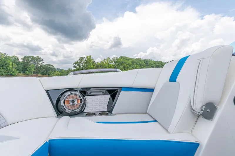 Slide: The Image of 2019 MasterCraft X24 boat interior with white and blue seating under cloudy sky. - 11