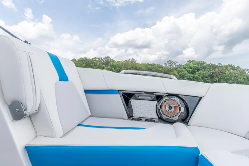 Slide: The Image of 2019 MasterCraft X24 boat interior with white and blue seating under cloudy sky. - 12