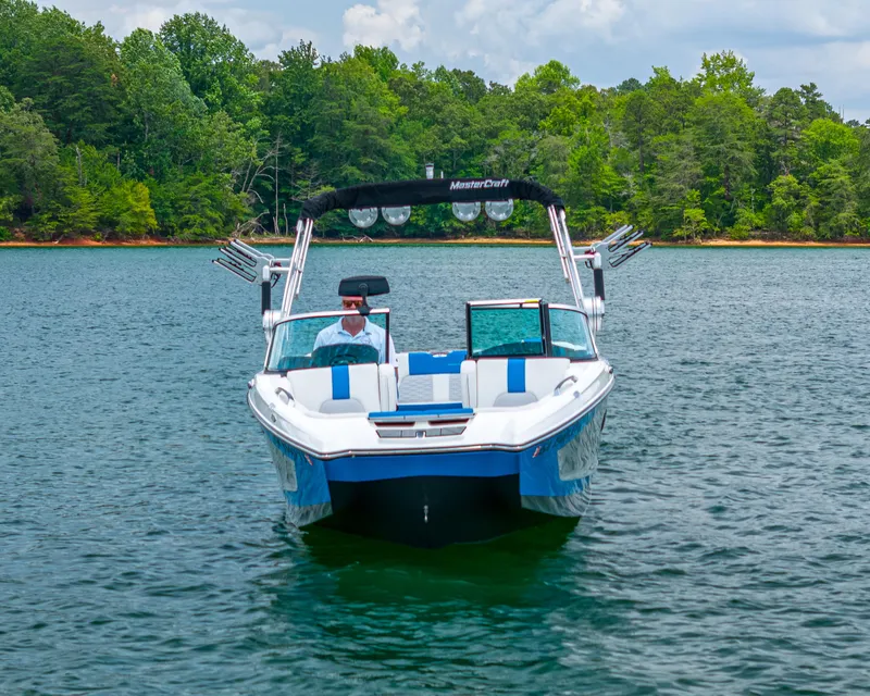 Slide: The Image of 2019 MasterCraft X24 boat on a serene lake with lush green trees. - 3