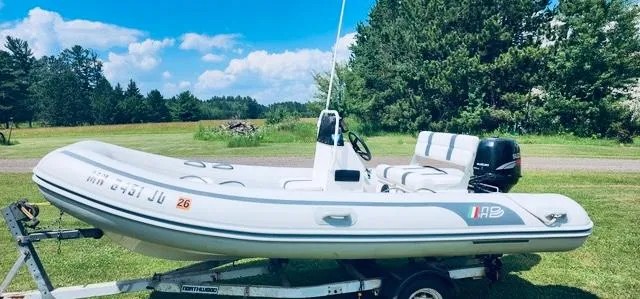 Slide: The Image of 2004 AB Inflatables Oceanus 4.30VST boat on trailer, set against a lush green landscape. - 0