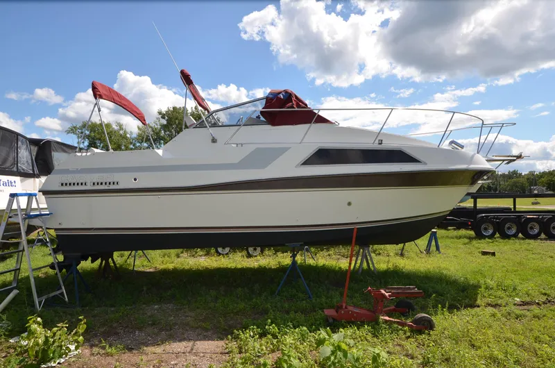 The Image of 1988 Carver 27 Montego boat on stands, outdoors, under a partly cloudy sky. - 0