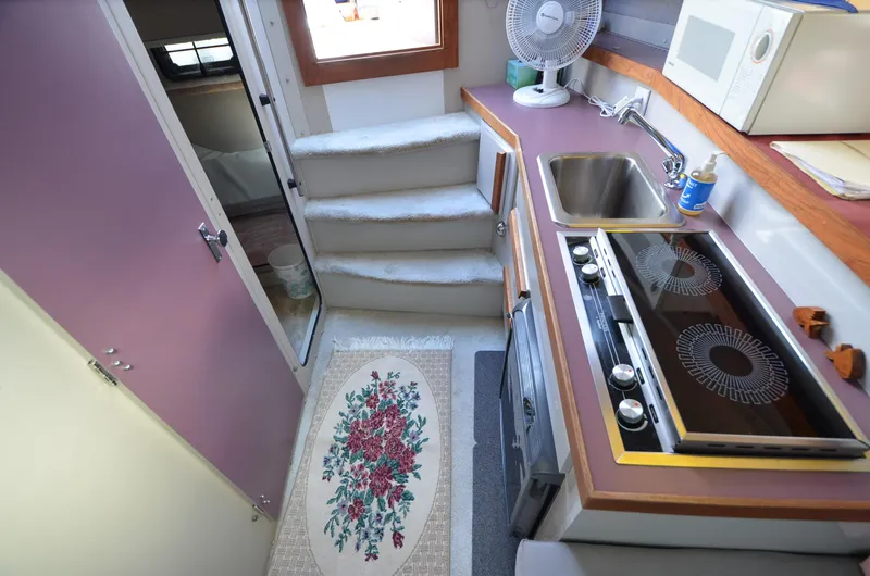 Slide: The Image of 1988 Carver 27 Montego interior kitchen with stove, sink, microwave, and floral rug. - 16