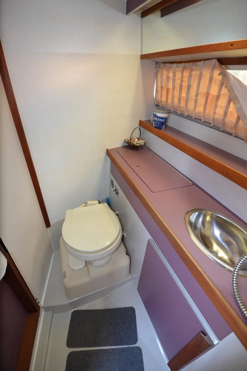 Slide: The Image of 1988 Carver 27 Montego boat bathroom with toilet, sink, and storage shelves. - 20