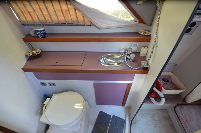 Slide: The Image of 1988 Carver 27 Montego boat bathroom with sink, toilet, and storage shelves. - 21