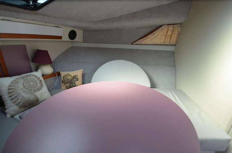Slide: The Image of 1988 Carver 27 Montego cabin interior with round table, cushions, and lamp. - 23