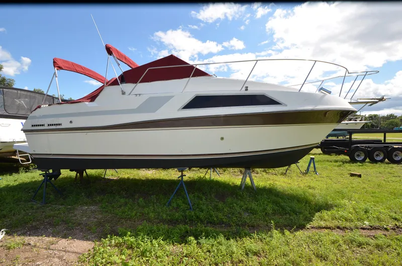 Slide: The Image of 1988 Carver 27 Montego boat with red canopy on grassy field. - 4