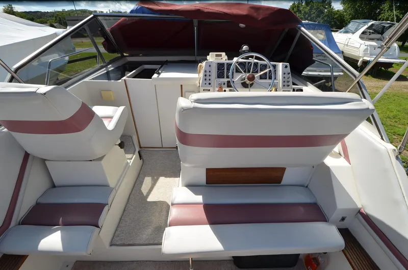 Slide: The Image of 1988 Carver 27 Montego boat interior with white and maroon seating, steering wheel, and dashboard. - 8