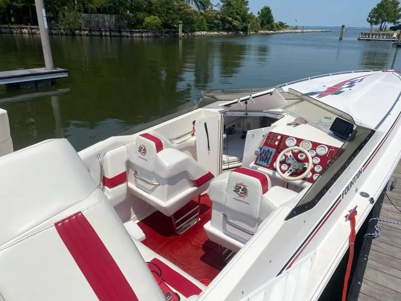 Slide: The Image of 2001 Fountain Lightning Executioner 35 boat with red and white interior docked by a calm river. - 4