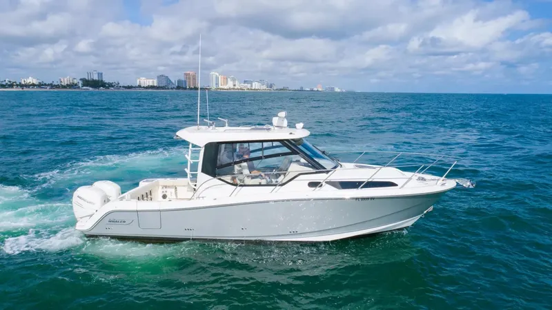 Slide: The Image of 2020 Boston Whaler 325 Conquest cruising on open water with city skyline in background. - 1