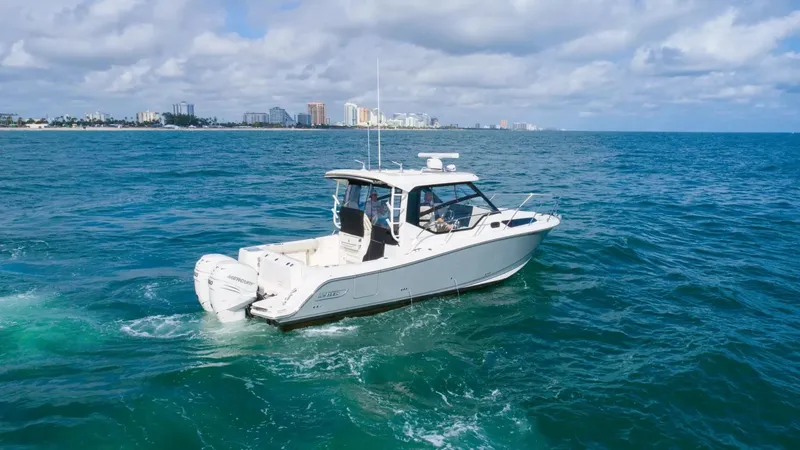 Slide: The Image of 2020 Boston Whaler 325 Conquest cruising on open water with city skyline in background. - 10