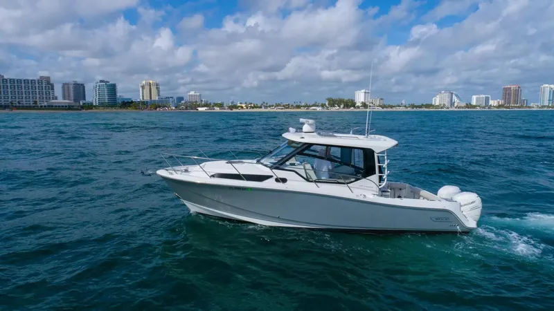 Slide: The Image of 2020 Boston Whaler 325 Conquest cruising on ocean near city skyline. - 2