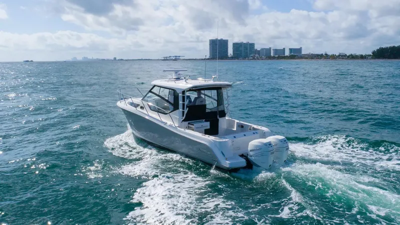 Slide: The Image of 2020 Boston Whaler 325 Conquest cruising on open water near city skyline. - 3
