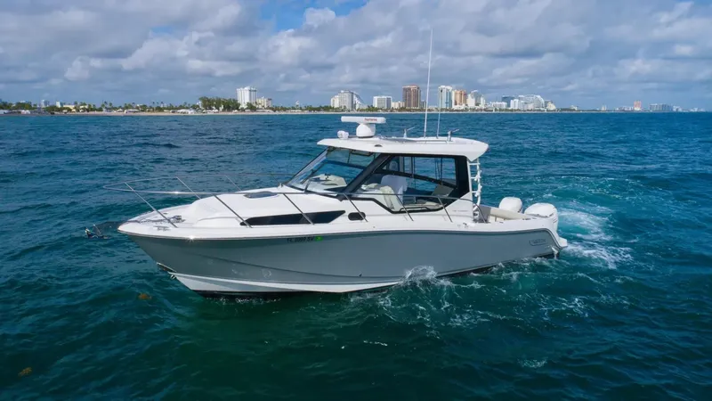 Slide: The Image of 2020 Boston Whaler 325 Conquest cruising on the ocean near a coastal city. - 4