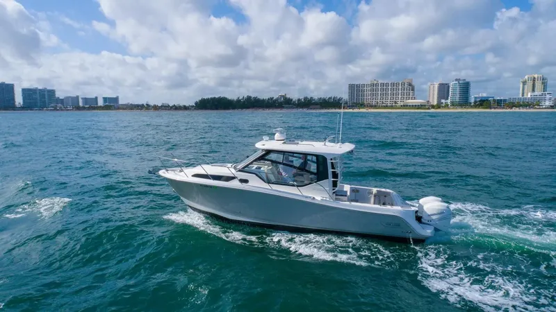 Slide: The Image of 2020 Boston Whaler 325 Conquest cruising on open water near city skyline. - 5