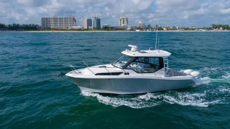 Slide: The Image of 2020 Boston Whaler 325 Conquest cruising on the ocean near a coastal city. - 6