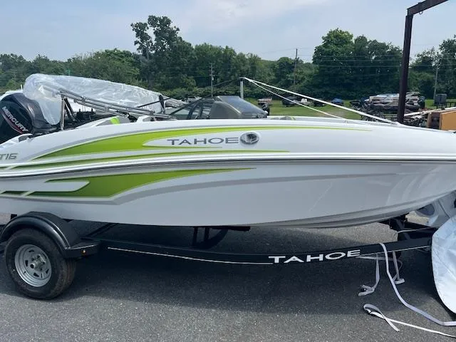 Slide: The Image of 2024 Tahoe T16 boat with green accents on a trailer, parked outdoors. - 0