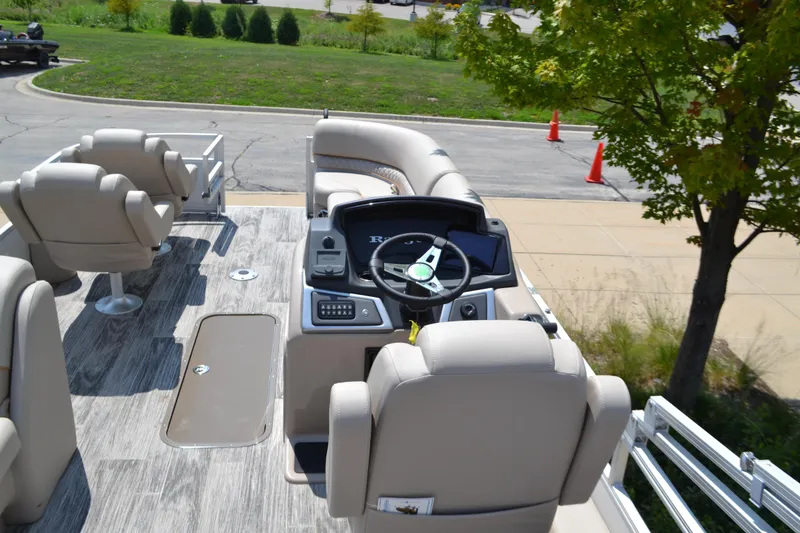 Slide: The Image of 2024 Ranger Reata 223FC boat interior with steering console and seating, parked outdoors. - 4