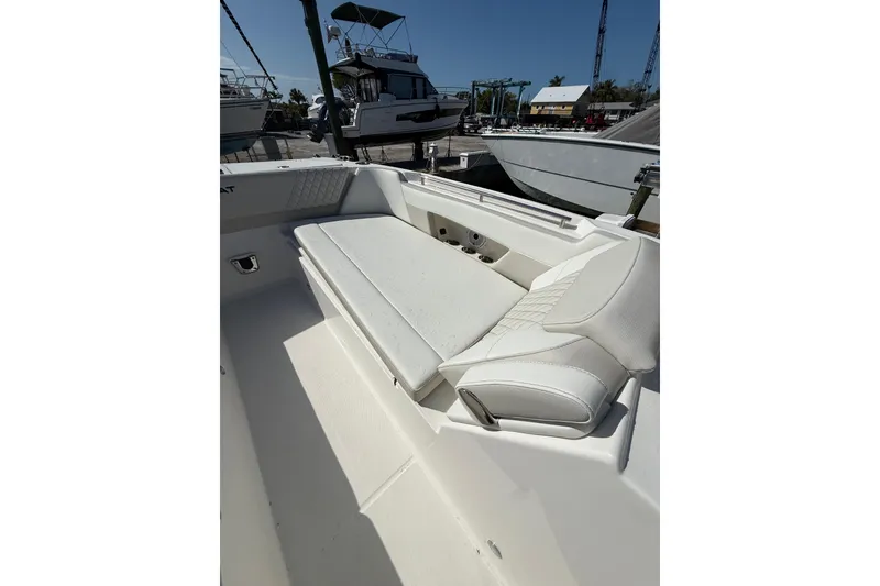Slide: The Image of 2026 World Cat 325 DC boat interior with white cushioned seating at a marina. - 20