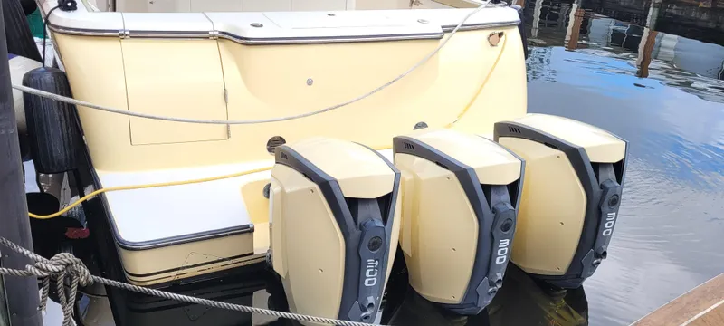 Slide: The Image of 2019 Altima Xcape Sport 38 SFE boat with triple outboard engines docked in water. - 20