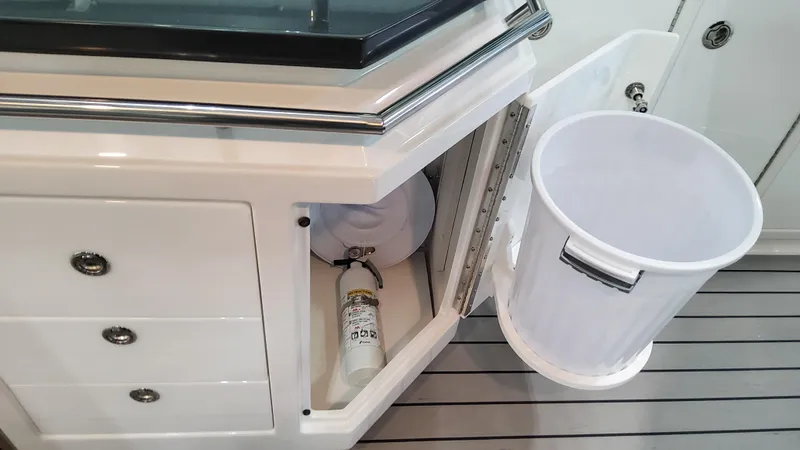 Slide: The Image of 2025 Formula 380 Super Sport Crossover OB interior storage with fire extinguisher and trash bin. - 42