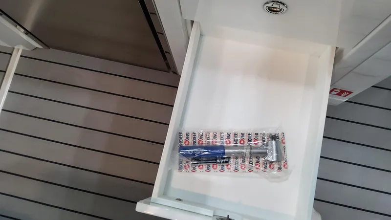 Slide: The Image of Open drawer on a 2025 Formula 380 Super Sport Crossover OB boat with a packaged tool inside. - 44