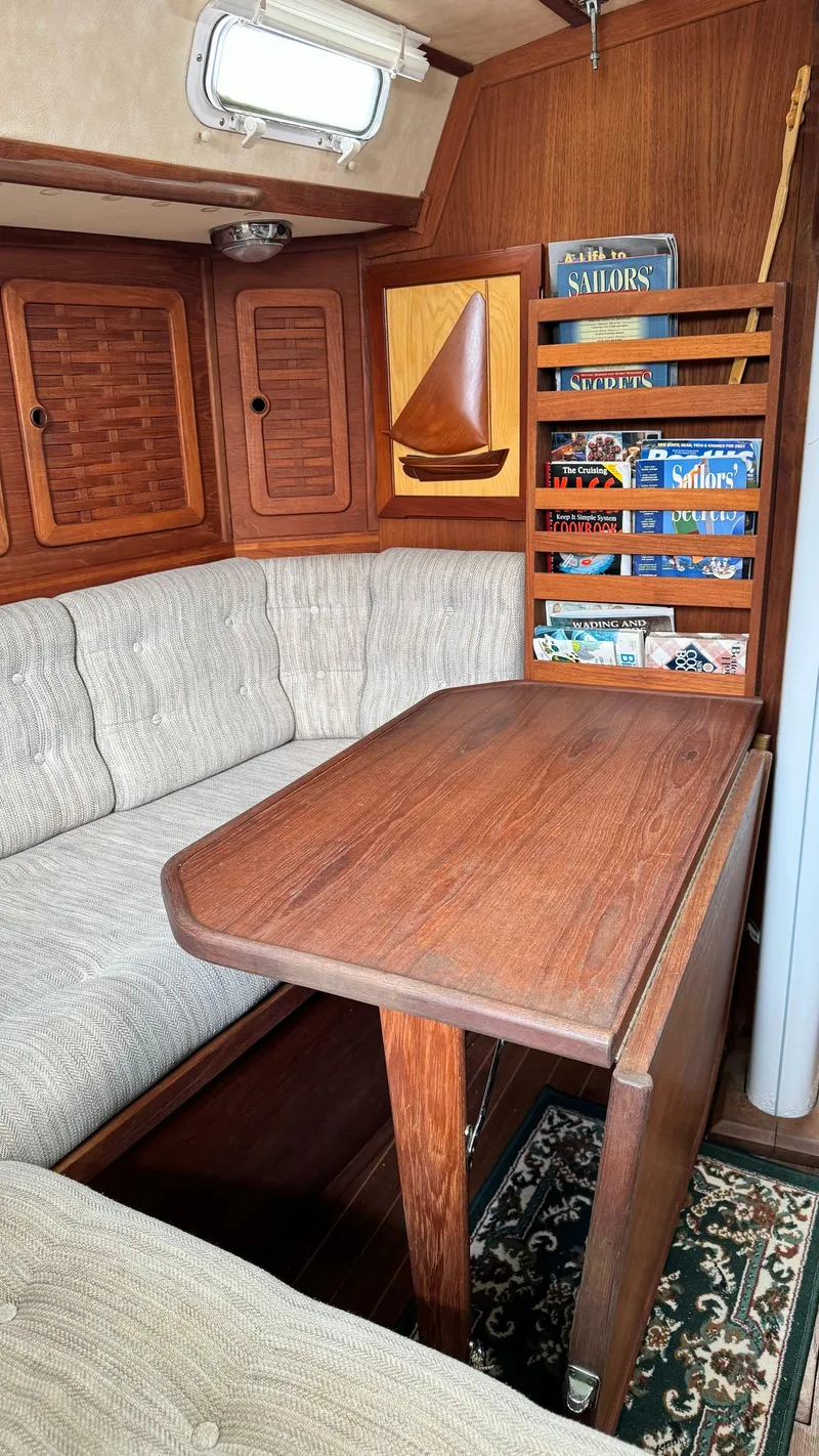 Slide: The Image of 1990 Sabre 38 sailboat interior with wooden table, cushioned seating, and bookshelf. - 10
