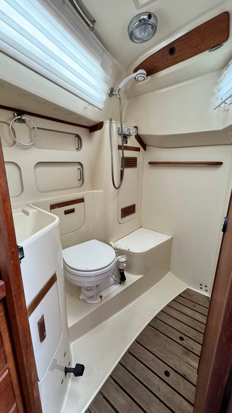 Slide: The Image of 1990 Sabre 38 yacht bathroom with shower, toilet, and wooden flooring. - 23