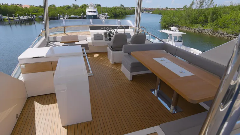 Slide: The Image of 2014 Fairline Squadron 78 Custom yacht deck with seating and helm, overlooking serene waterway. - 15