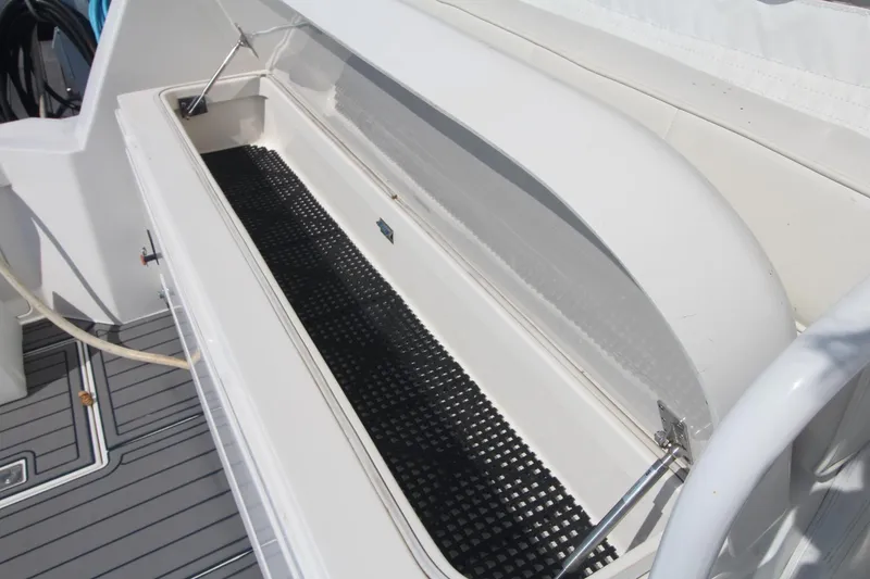Slide: The Image of 2013 Cabo 40 Hardtop Express boat storage compartment with open lid and black mat. - 15