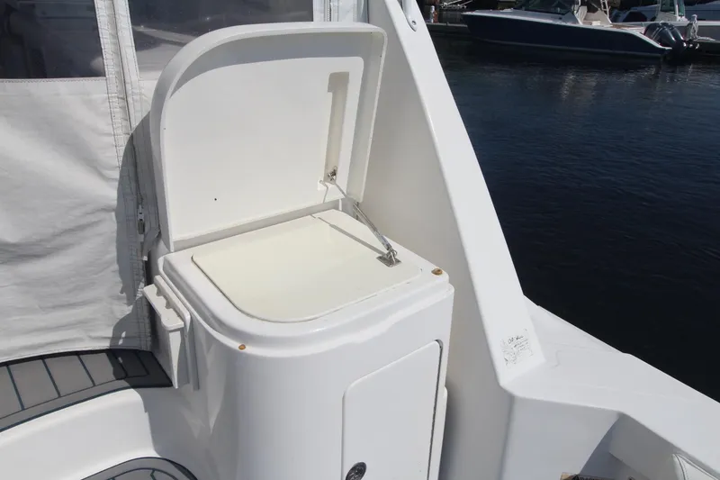 Slide: The Image of Open storage compartment on 2013 Cabo 40 Hardtop Express boat, docked by the water. - 16