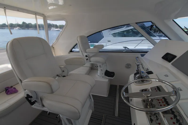 Slide: The Image of 2013 Cabo 40 Hardtop Express yacht interior with white leather seating and modern helm controls. - 18