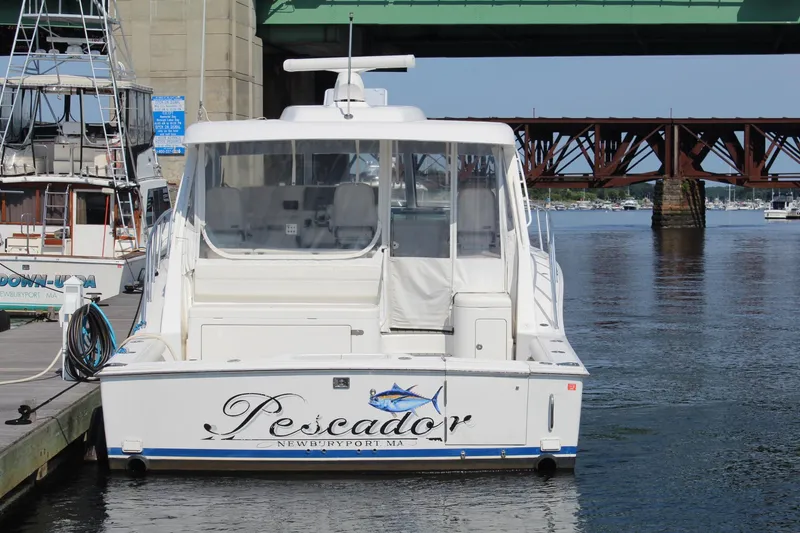 Slide: The Image of 2013 Cabo 40 Hardtop Express boat docked near a bridge, named "Pescador." - 2