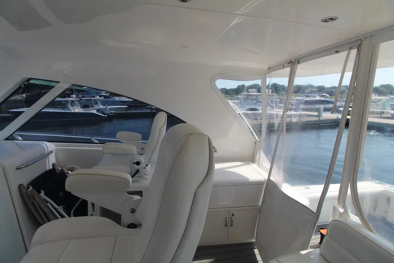 Slide: The Image of Interior view of 2013 Cabo 40 Hardtop Express yacht with white seating and marina backdrop. - 22