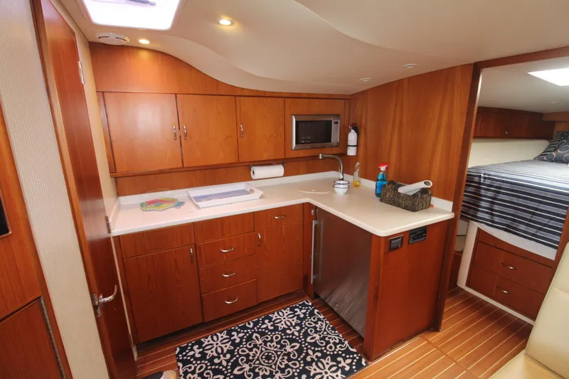 Slide: The Image of 2013 Cabo 40 Hardtop Express yacht interior with wooden cabinetry and modern kitchen amenities. - 29
