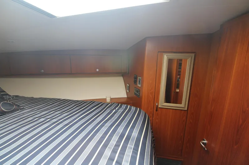 Slide: The Image of Interior cabin of 2013 Cabo 40 Hardtop Express with striped bedding and wooden paneling. - 40