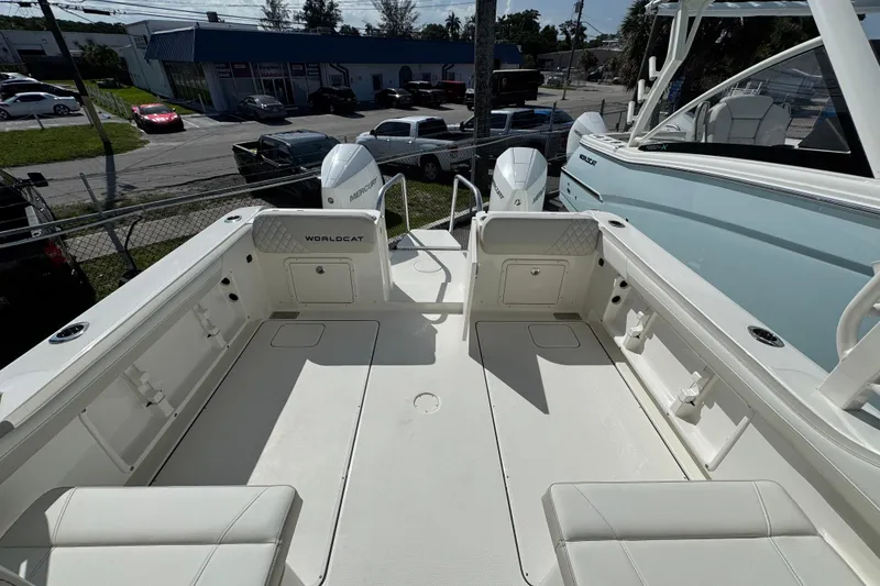 Slide: The Image of 2025 World Cat 296 DC boat interior with dual Mercury engines, parked outdoors. - 7