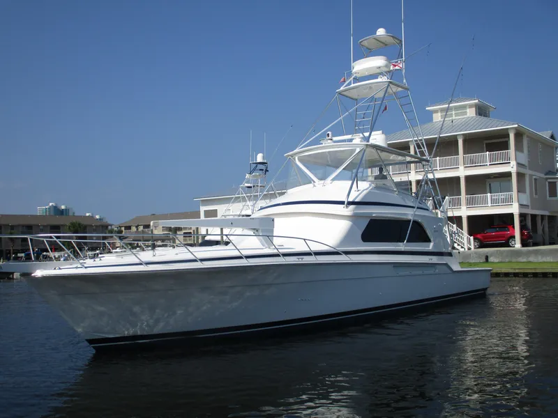 Slide: The Image of 2000 Bertram 60 Convertible yacht docked near waterfront buildings. - 0