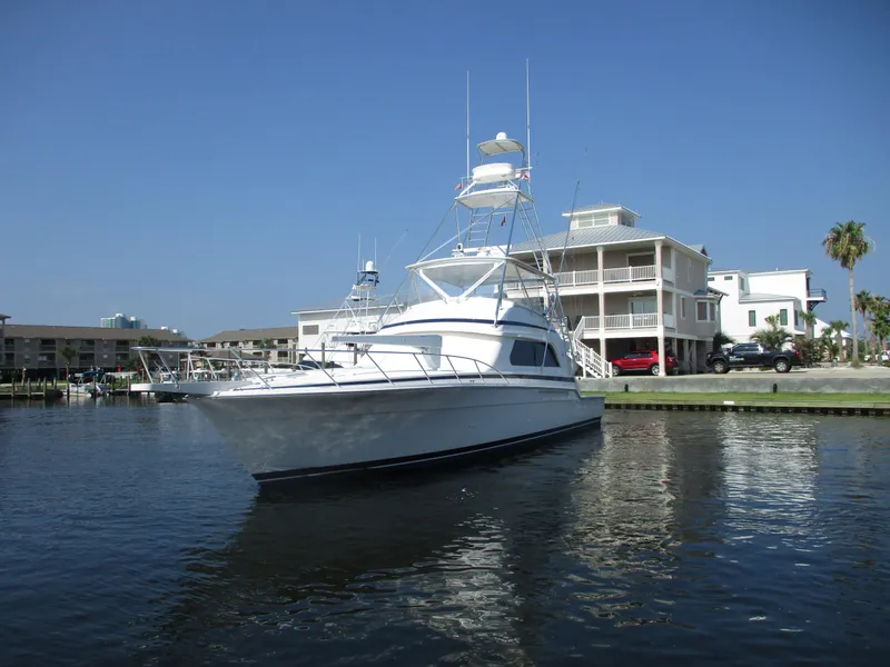 Slide: The Image of 2000 Bertram 60 Convertible yacht docked near waterfront homes. - 10