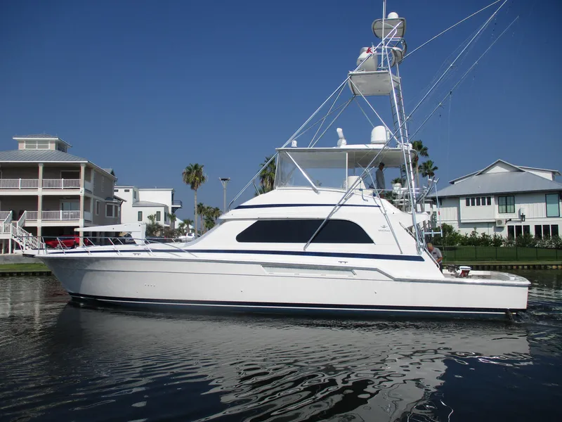 Slide: The Image of 2000 Bertram 60 Convertible yacht docked near waterfront homes. - 2
