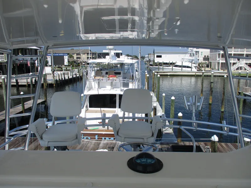 Slide: The Image of Bertram 60 Convertible yacht, 2000 model, docked at a marina with scenic waterfront view. - 23