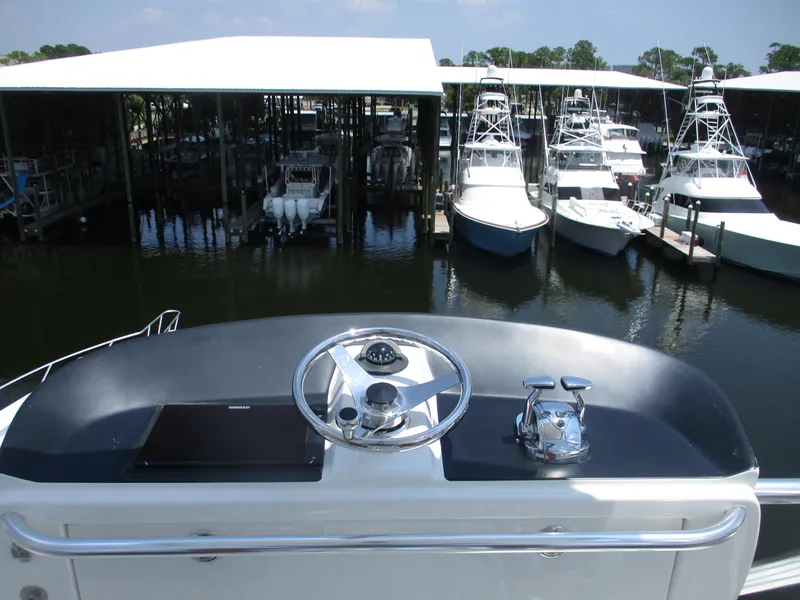 Slide: The Image of Bertram 60 Convertible 2000 yacht helm overlooking marina with docked boats. - 26