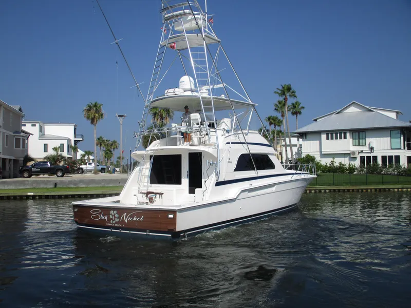 Slide: The Image of 2000 Bertram 60 Convertible yacht cruising in a scenic waterfront area. - 4