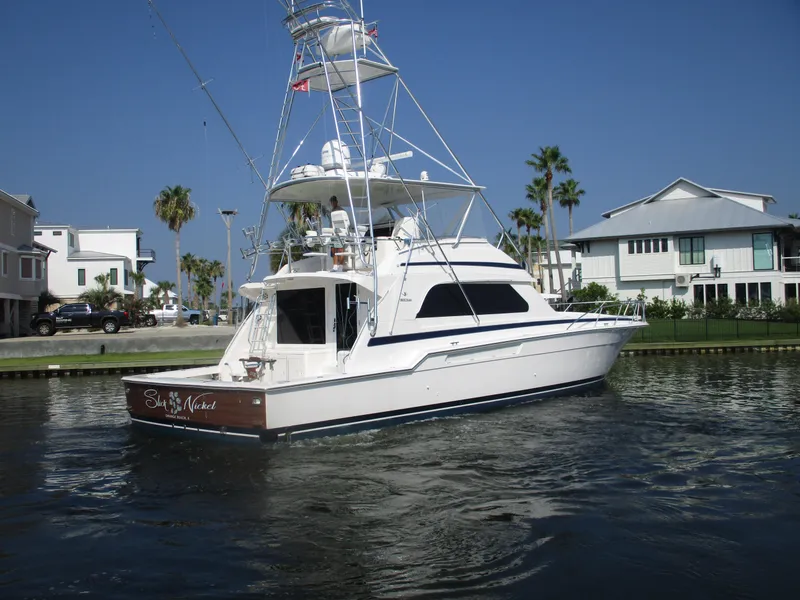 Slide: The Image of Bertram 60 Convertible 2000 yacht on calm water near waterfront homes. - 5