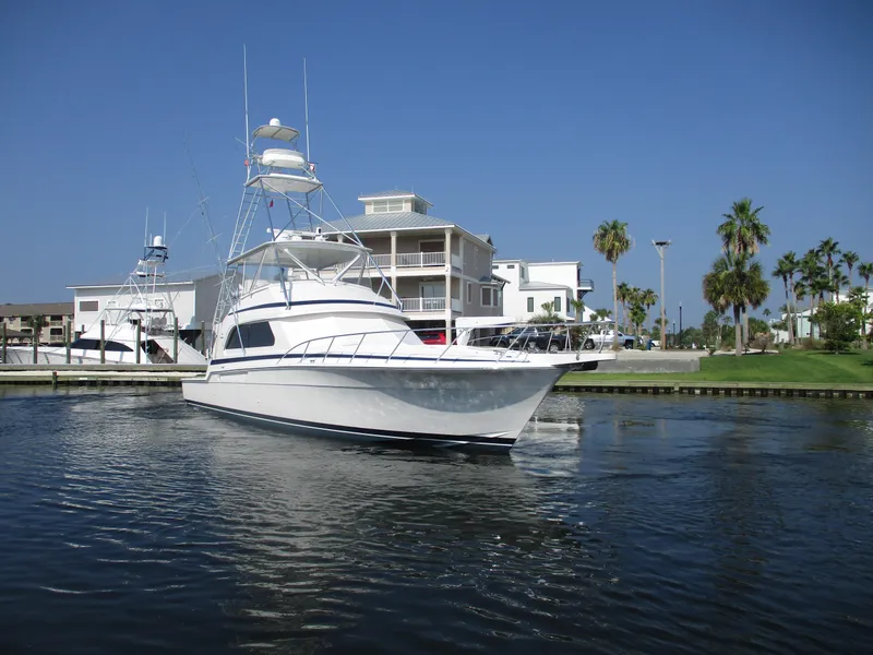 Slide: The Image of 2000 Bertram 60 Convertible yacht docked near waterfront homes. - 8