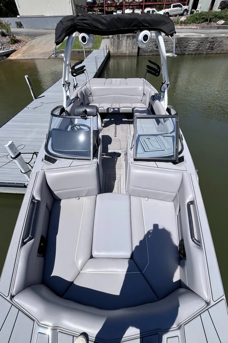 Slide: The Image of 2024 Moomba Max boat with sleek gray interior, docked by the water. - 2