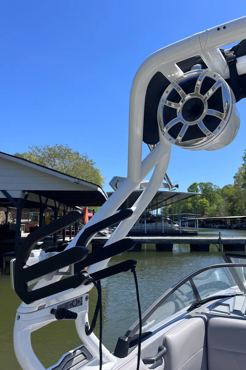 Slide: The Image of 2024 Moomba Max boat with wakeboard tower and speaker, docked by a lakeside. - 21