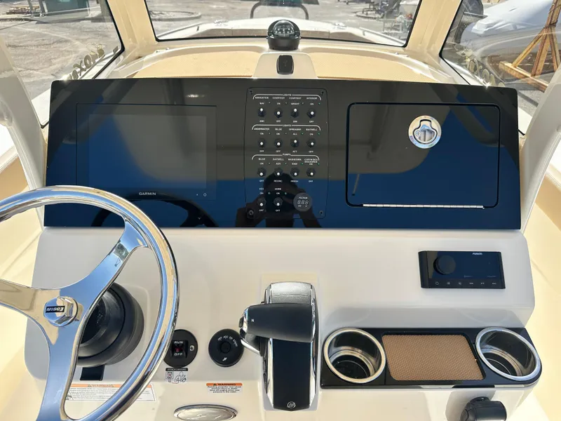 Slide: The Image of 2025 Scout 240 XSF boat dashboard with steering wheel, controls, and cup holders. - 11