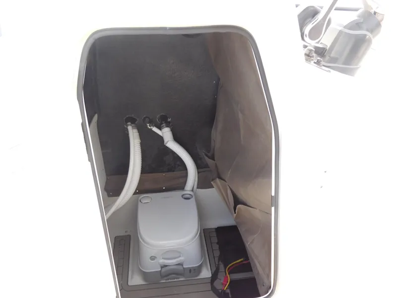 Slide: The Image of 2024 Stingray 216 CC boat interior storage compartment with portable toilet. - 23